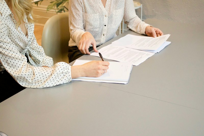 Woman signing paperwork beside another woman